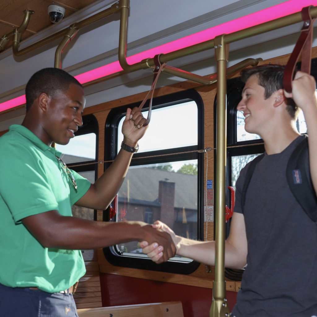 two students shaking hands on the bus
