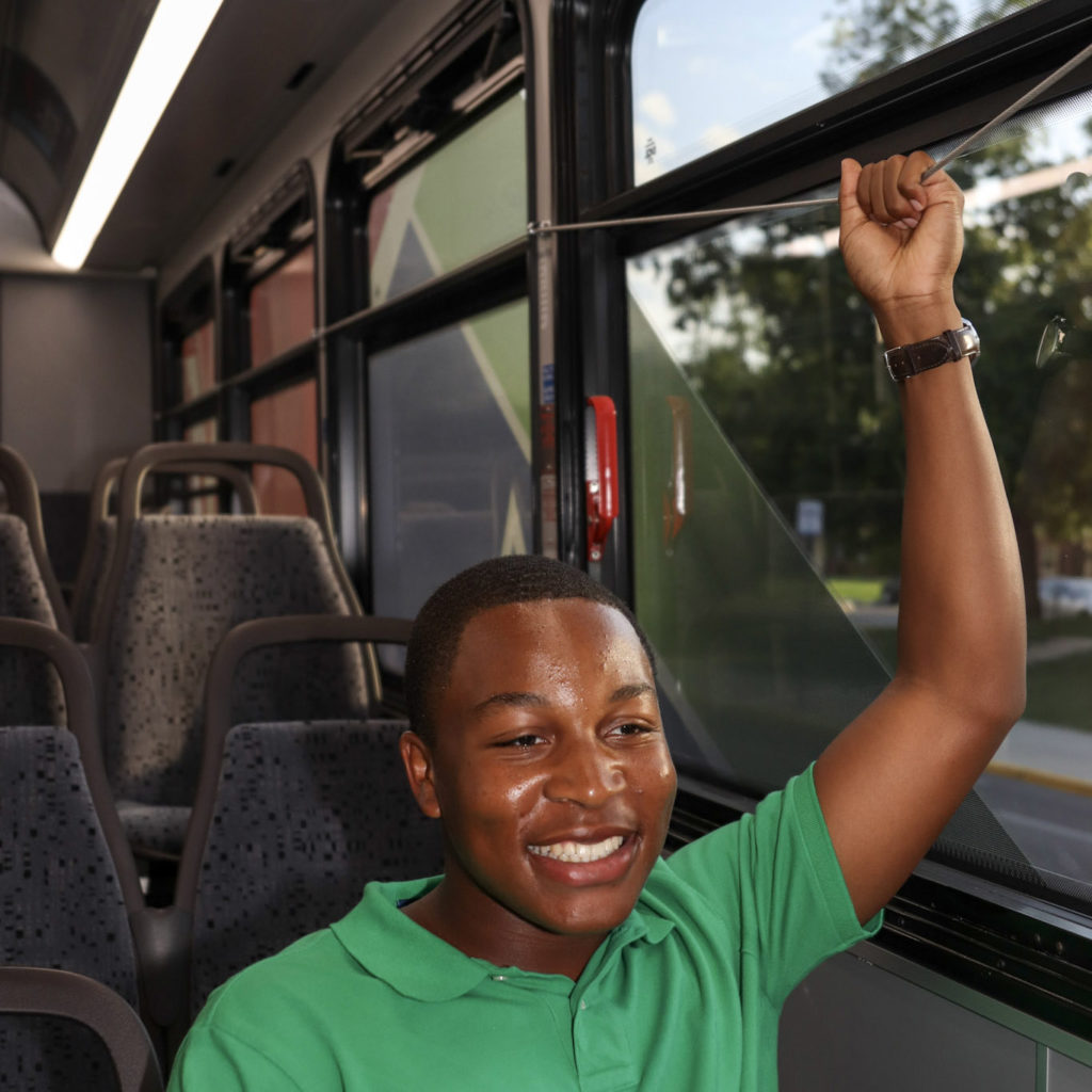 boy riding bus holding stop cord