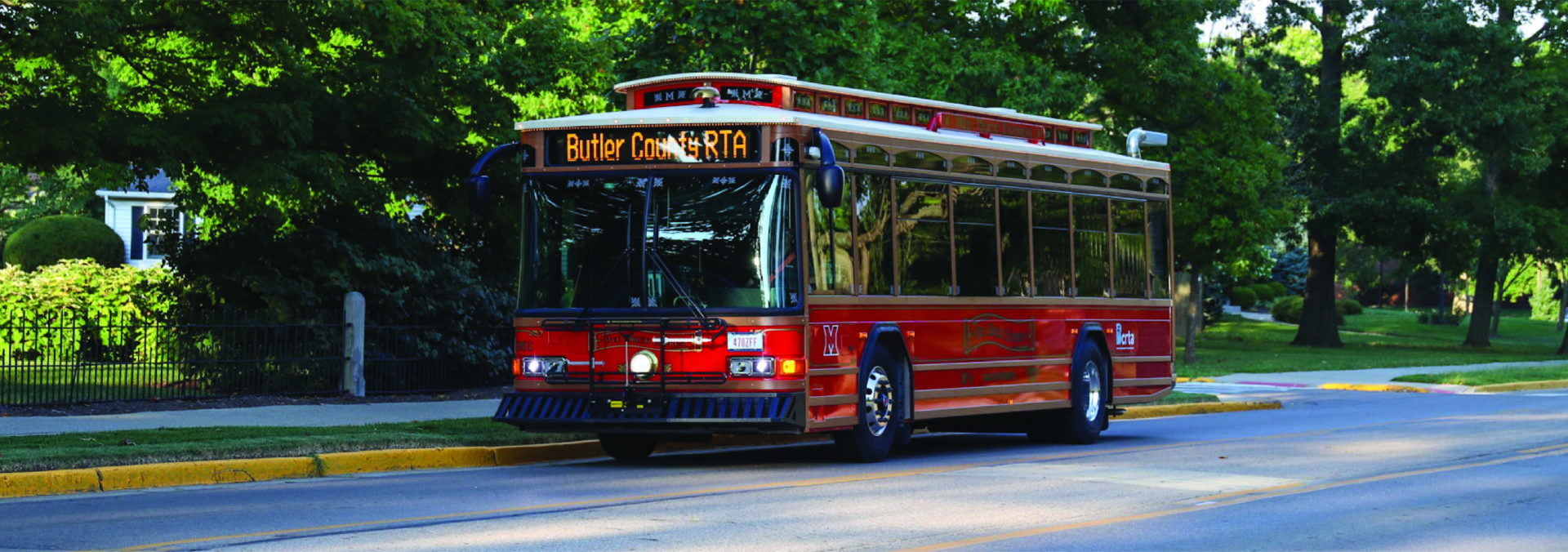 Red Bus on road by trees
